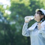 熱中症対策のため水分補給をする工事現場の女性従業員