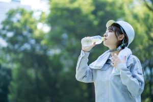 熱中症対策のため水分補給をする工事現場の女性従業員