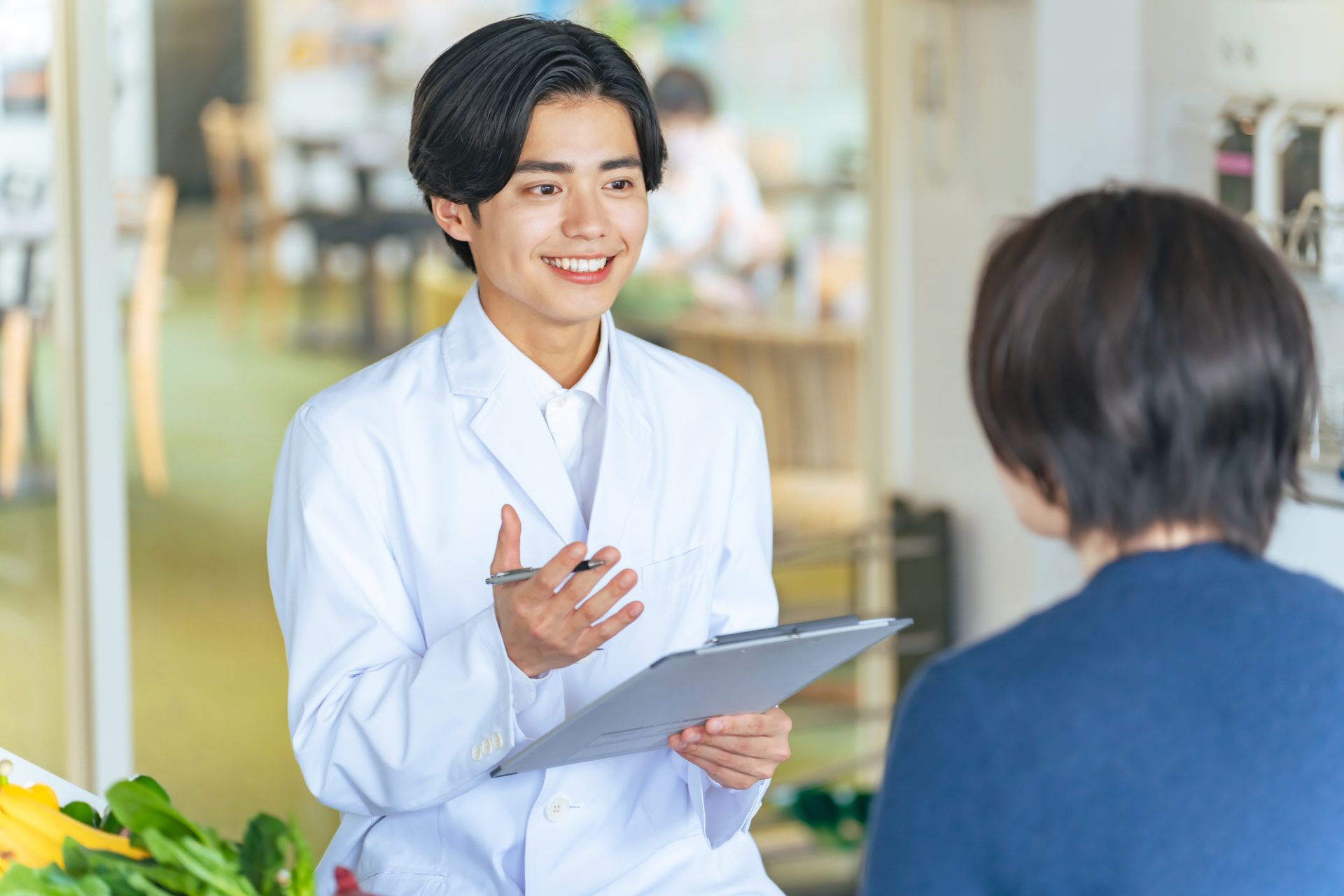 女性と会話する若い白衣の男性医師