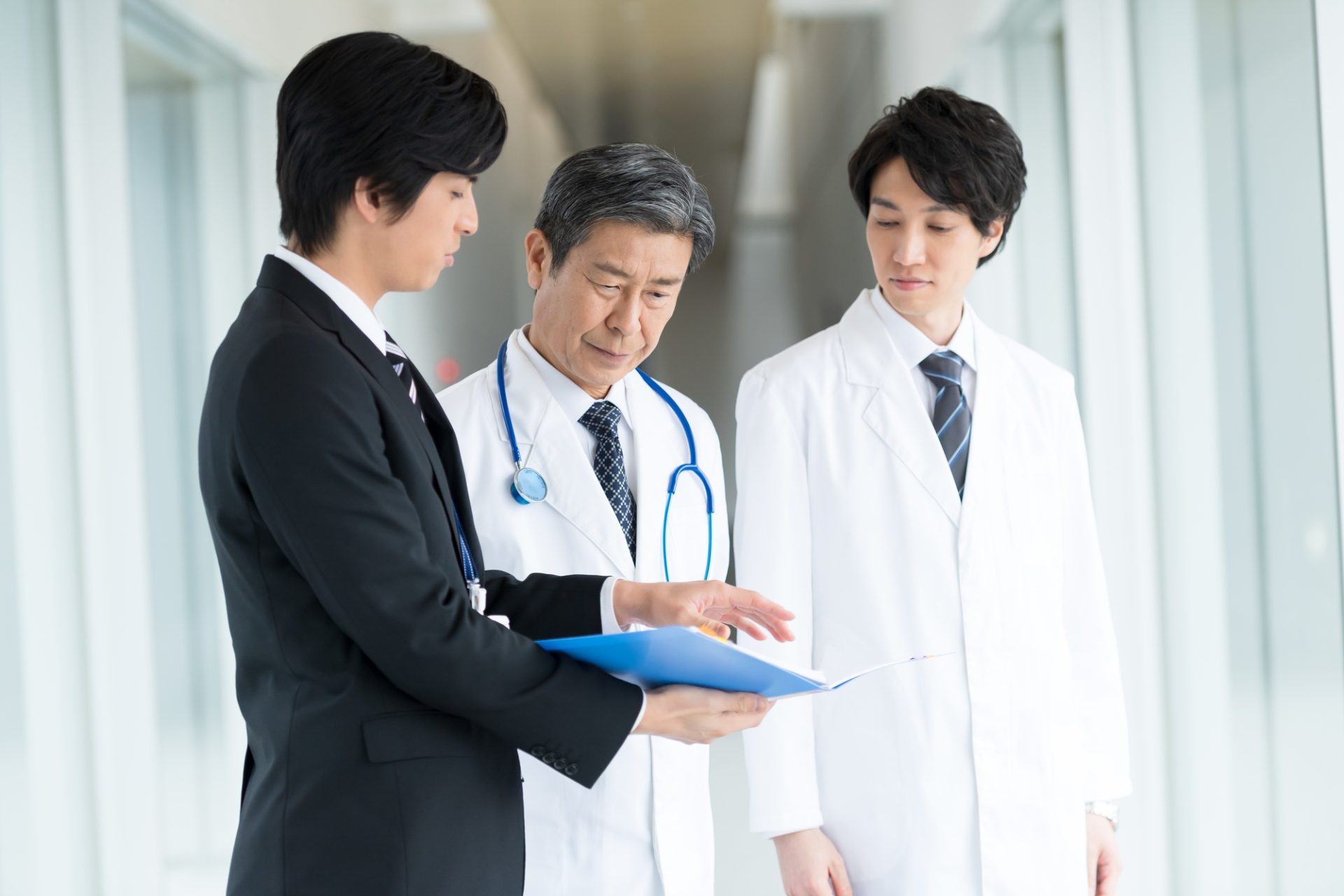 病院でビジネスマンと話す男性医師二人
