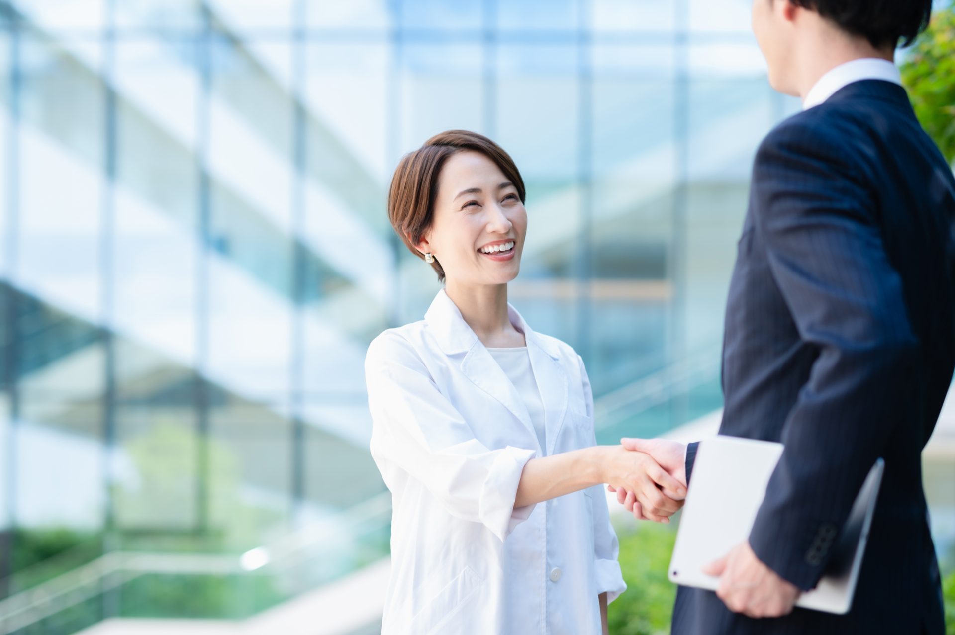 握手する女性医師とビジネスマン