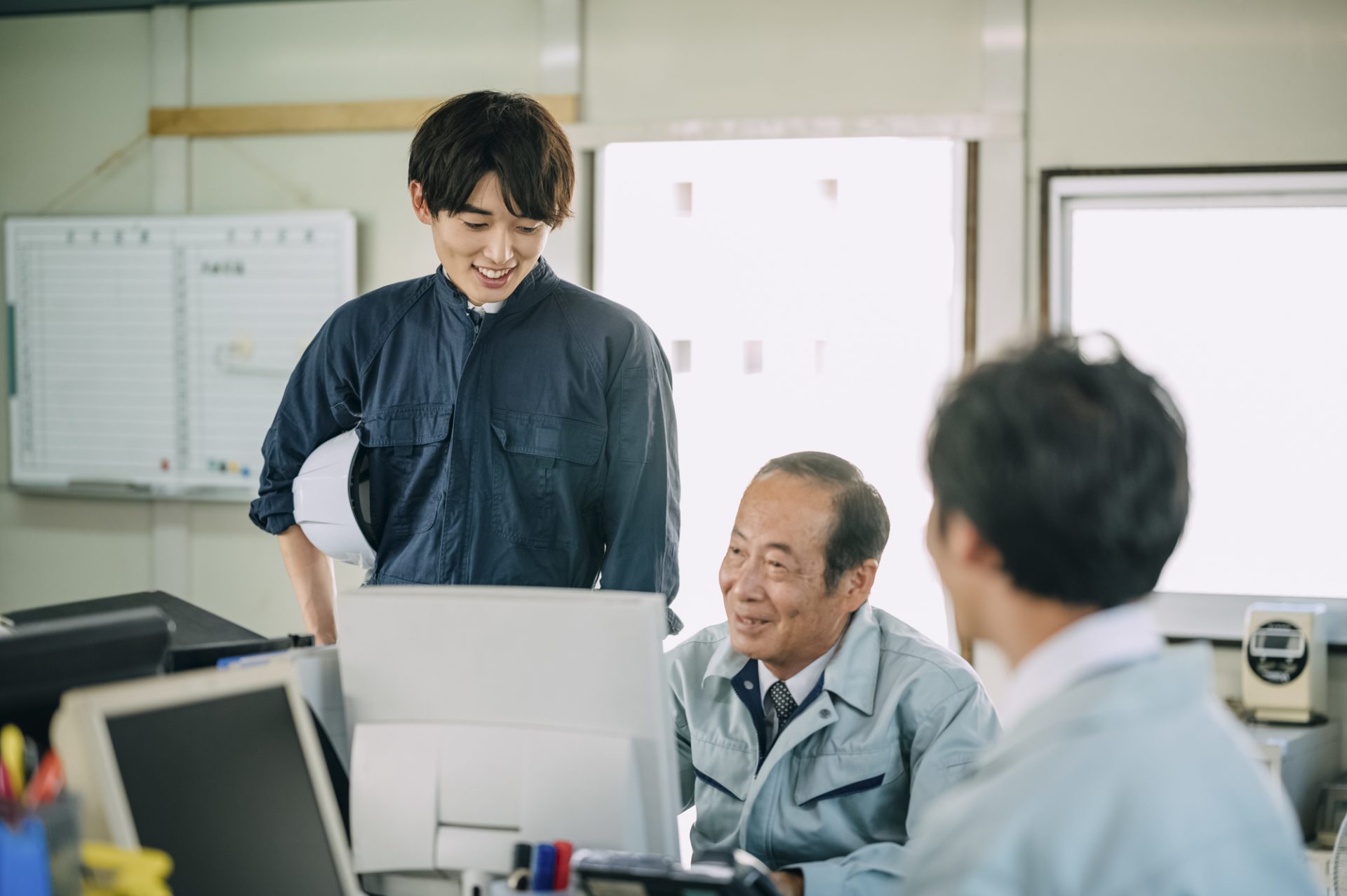 事務所で談笑をする作業着の男性たち